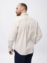 Camisa de manga larga con estampado de cuadros finos, cuello clásico con botones y cierre frontal. Presenta un bordado pequeño en la pechera y puños abotonados.