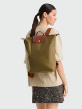 Mochila Longchamp de la línea Le Pliage Original, tamaño M, en color rosado con solapa y asas de cuero marrón.
