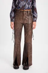 Pantalón de cuero color chocolate con efecto desgastado, de corte recto y tiro medio. Presenta costuras verticales en el frente y tajos laterales en el ruedo que aportan movimiento.