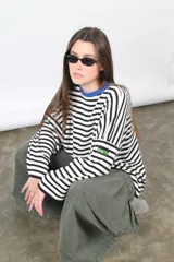Sweater oversize de punto a rayas horizontales blancas y negras, con cuello redondo azul y parche bordado con la palabra 'BONITA' en la manga.