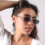Lentes de sol con marco metálico plateado de forma rectangular y cristales oscuros. Presentan un diseño minimalista con detalle de logo en la patilla.