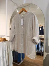 Camisa de lino color beige, con cuello mao, mangas largas remangables y cierre frontal con botones.
