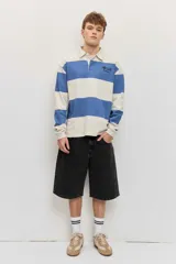 Chomba de friza de manga larga con diseño de rayas horizontales anchas en color beige y azul, cuello polo y pequeño bordado en el pecho.