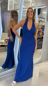 Vestido largo de fiesta color azul eléctrico con acabado brillante. Presenta un diseño con escote halter profundo, espalda descubierta y detalle de fruncido en la cintura que estiliza la figura.