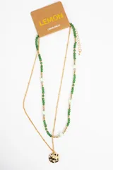 Collar doble compuesto por una cadena fina dorada con dije circular texturizado y otra tira de cuentas verdes y doradas con detalles translúcidos.
