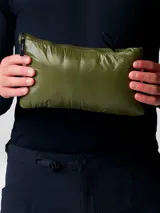 Campera ultraligera de plumas Mountain Hardwear, modelo Ghost Whisperer, en color verde oliva. Presenta un diseño acolchado con tejido ripstop, cierre frontal completo, cuello alto y bolsillos laterales con cremallera.