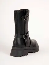 Bota alta negra de estilo rocker, con suela track gruesa, hebilla decorativa en la parte superior y tiras con tachas y argolla metálica en el tobillo.