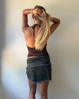 Minifalda de jean color negro con efecto desgastado, diseño de tajo frontal y cinturón integrado con hebilla metálica grande.