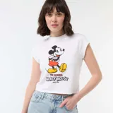 Camiseta blanca de corte cropped con estampado frontal de Mickey Mouse y texto alusivo a Disney.