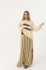 Sweater color manteca de tejido de punto con cuello redondo y ribete marrón. Presenta dos peces marrones tejidos en el frente con detalles bordados a mano.