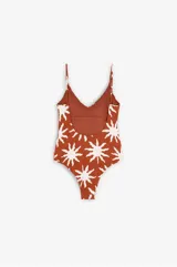 Bañador enterizo con escote en V y espalda abierta, estampado con diseño de soles en color crudo sobre fondo terracota. Cuenta con copas extraíbles y tirantes regulables.