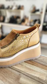 Zapatos de cuero color tostado con plataforma alta, cierre frontal y detalles en gamuza y textura símil cocodrilo en tonos dorados.