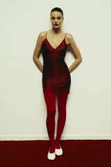 Vestido corto color rojo oscuro (vino) con escote en V pronunciado y tirantes finos. Presenta un diseño con flecos o tiras superpuestas que caen verticalmente y terminación en encaje festoneado en el ruedo y el escote.
