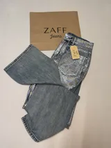 Pantalón de jean celeste con estampado de cuadrados plateados reflectantes.