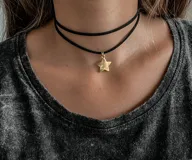 Gargantilla doble de cuero negro con dije de estrella dorada.
