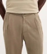 Pantalón recto de viscolino liso color beige, con cierre de botón y cremallera, y bolsillos tipo cuchillo.