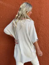 Blusa de corte holgado y diseño minimalista, confeccionada en tela texturizada color beige, con escote en V y mangas cortas tipo kimono.