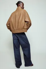 Chaqueta bomber ZW Collection confeccionada en tejido efecto piel de color marrón. Cuenta con cuello subido, manga larga con puño y botón a presión, bolsillos delanteros y bajo recto elástico. Cierre frontal cruzado con botones a presión.