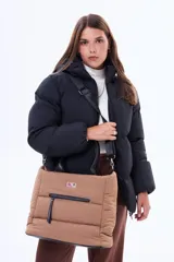 Bolso tipo tote acolchado de color tostado, con manijas fijas negras y correa ajustable desmontable. Presenta un bolsillo frontal con cierre y un diseño práctico con compartimento principal espacioso.