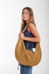 Cartera hobo grande de cuero descarne color marrón, con correa de hombro ajustable y cierre superior con cremallera.