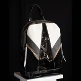 Mochila de cuero vacuno negra, blanca y gris, con detalles en charol y herrajes dorados. Tiene dos bolsillos frontales con cierre y un bolsillo trasero. El interior está forrado y cuenta con un bolsillo con cierre y otro pequeño para el celular.