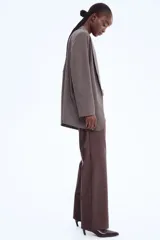 Pantalón de tejido revestido color marrón oscuro, de corte recto y tiro alto, con pretina prolongada y cierre frontal.