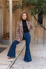 Jeans de corte flare color azul oscuro, tiro alto y diseño ajustado en las piernas que se ensancha gradualmente desde las rodillas hacia el dobladillo.