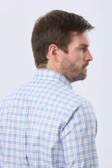 Camisa de manga larga con diseño a cuadros en tonos celeste, azul y blanco, con cuello abotonado y cierre frontal con botones.