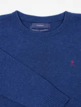 Sweater azul de lana merino con cuello redondo y logo bordado en rojo en el pecho.