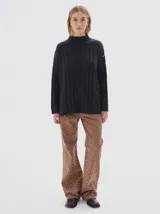 Buzo tejido de punto color beige, con cuello subido, diseño oversized y aberturas laterales en el ruedo.