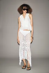 Falda midi semitransparente de punto crochet color blanco, con cintura elástica y bajo asimétrico con flecos.