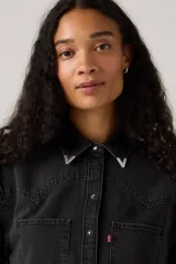 Camisa de jean negra con estilo western, cuello clásico, cierre de botones a presión, dos bolsillos frontales con solapa y detalles de costuras en el canesú.