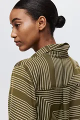 Camisa verde militar con estampado geométrico de líneas blancas, cuello clásico, botones frontales y mangas largas con puños abotonados.