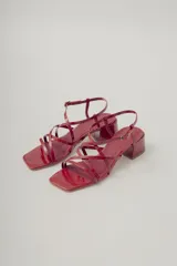 Sandalia de tiras finas color rojo brillante, con puntera cuadrada y taco ancho de altura media. Posee tira ajustable con hebilla en el tobillo.