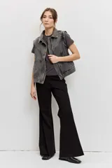 Chaleco de denim color gris deslavado, con cuello camisero, cierre frontal con botones metálicos y costuras decorativas.