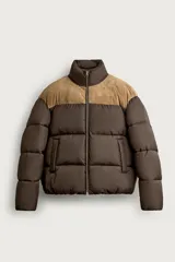 Cazadora puffer relaxed fit color marrón con canesú superior en tono tostado de acabado aterciopelado. Cuenta con cuello subido, manga larga, bolsillos de vivo en la cadera, acabados en elástico y cierre frontal con cremallera.
