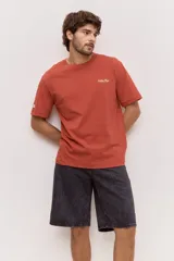 Remera blanca de algodón, de corte holgado y mangas cortas, con pequeño estampado azul en el pecho.