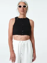 Top negro ajustado al cuerpo, con cuello redondo y cierre frontal con botones.