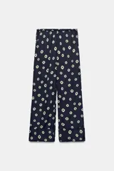 Pantalón de tiro medio con cintura elástica y bolsillos ocultos en costura. Presenta un diseño de corte recto con dobladillo ancho en el bajo y un estampado geométrico sobre fondo oscuro.