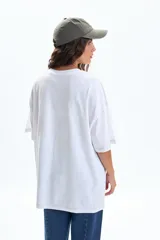 Remera oversize blanca de manga corta, con estampado frontal de flores en tonos bordó y texto "Esprit Fleuri Botanique Marseille, France".