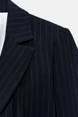 Blazer entallado de color azul marino con estampado de rayas diplomáticas, cuello con solapa, hombreras, manga larga y cierre frontal con un botón. Cuenta con bolsillos delanteros con solapa.