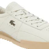 Championes Lacoste modelo Aura, color blanco con suela de goma en tono beige. Presentan un diseño minimalista de cuero con el logo del cocodrilo metálico en el lateral y detalles perforados.