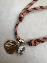 Gargantilla con cordón doble en tonos naranja y gris, con dije de concha dorada y dije de caracol blanco.