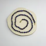 Collar de cuentas de lapislázuli de 6mm con separadores de hilo rojo y cierre de mosquetón dorado.