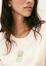 Pijama compuesto por una remera de algodón color crema con estampa pequeña en el pecho y un short de tela liviana color beige con estampado de cuadrícula fina.