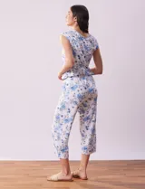 Conjunto de pijama marca René Rofé, compuesto por remera de mangas cortas con escote en V abotonado y pantalón capri con cintura elastizada. Diseño estampado con flores azules sobre fondo blanco.