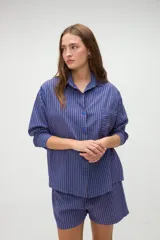 Camisa de manga larga de algodón, con diseño a rayas en tonos azules y morados, calce holgado, cuello camisero, cierre frontal con botones y un bolsillo aplicado en el pecho.