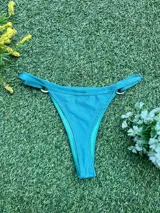Bikini de dos piezas color celeste metalizado, compuesto por un corpiño triangular con argolla central de zamak y una bombacha colaless con argollas ajustables en los laterales. Incluye copas soft removibles.