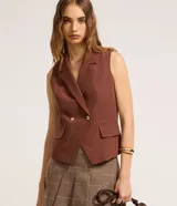 Chaleco marrón de corte sastre con cuello blazer, doble botonadura dorada y bolsillos simulados. Fabricado con procesos más sustentables.