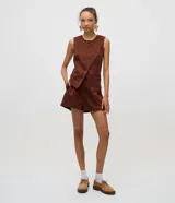 Short femenino evasé confeccionado en gamuza sintética color marrón, con cintura recta y fija, pliegues delanteros y bolsillos laterales tipo cuchillo.